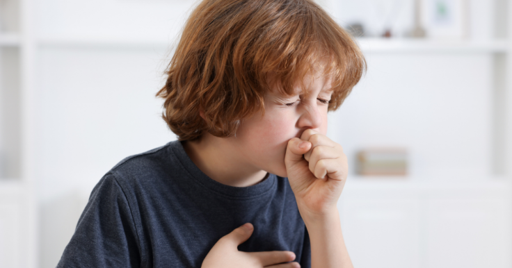 A child clutching his chest and coughing