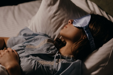 A woman sleeps in bed while wearing a sleep mask.