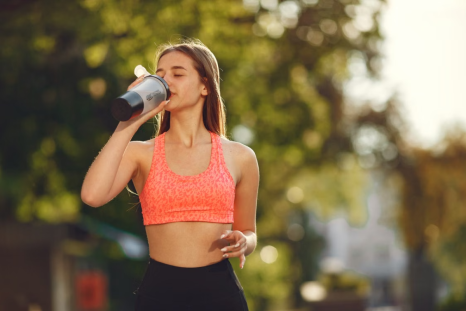 A woman drinks a protein shake in the middle of a workout.