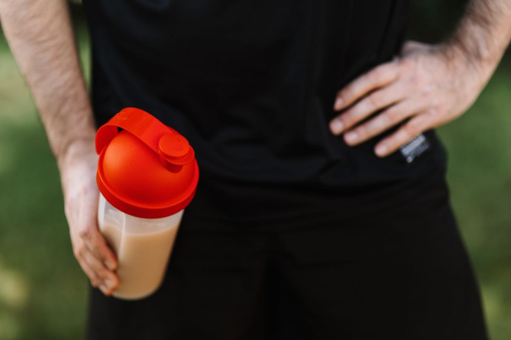 man holding a protein shake tumbler